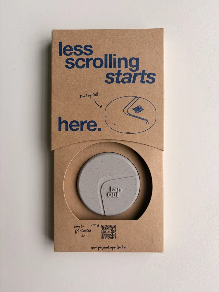 De Tap Out Home in de kartonnen verpakking, met op de voorkant de tekst less scrolling starts here